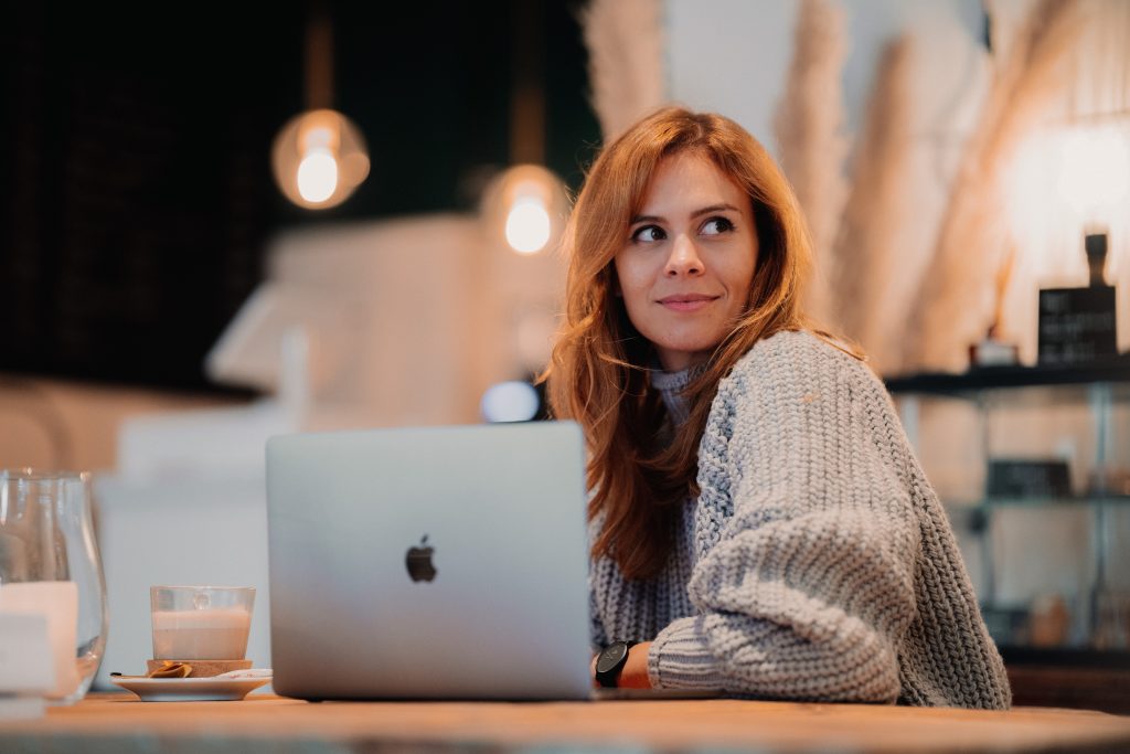 Lähiesimiestyö ammattitutkinto artikkelin otsikkokuva, jossa nainen istuu laptopin kanssa pöydän ääressä.